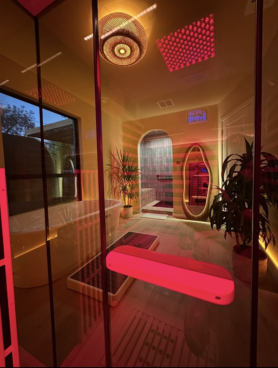 A private suite seen through the glass — infrared sauna, plunge tub and vanity